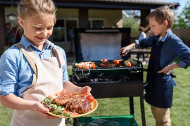 little girl holding plate with steaks clipart