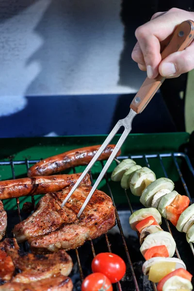 Hand pricking steak with barbecue fork — Free Stock Photo