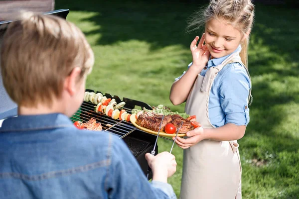 Kids preparing meat and vegetables on grill — Stock Photo, Image