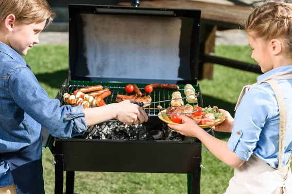 Barn förbereder kött och grönsaker på grillen — Stockfoto