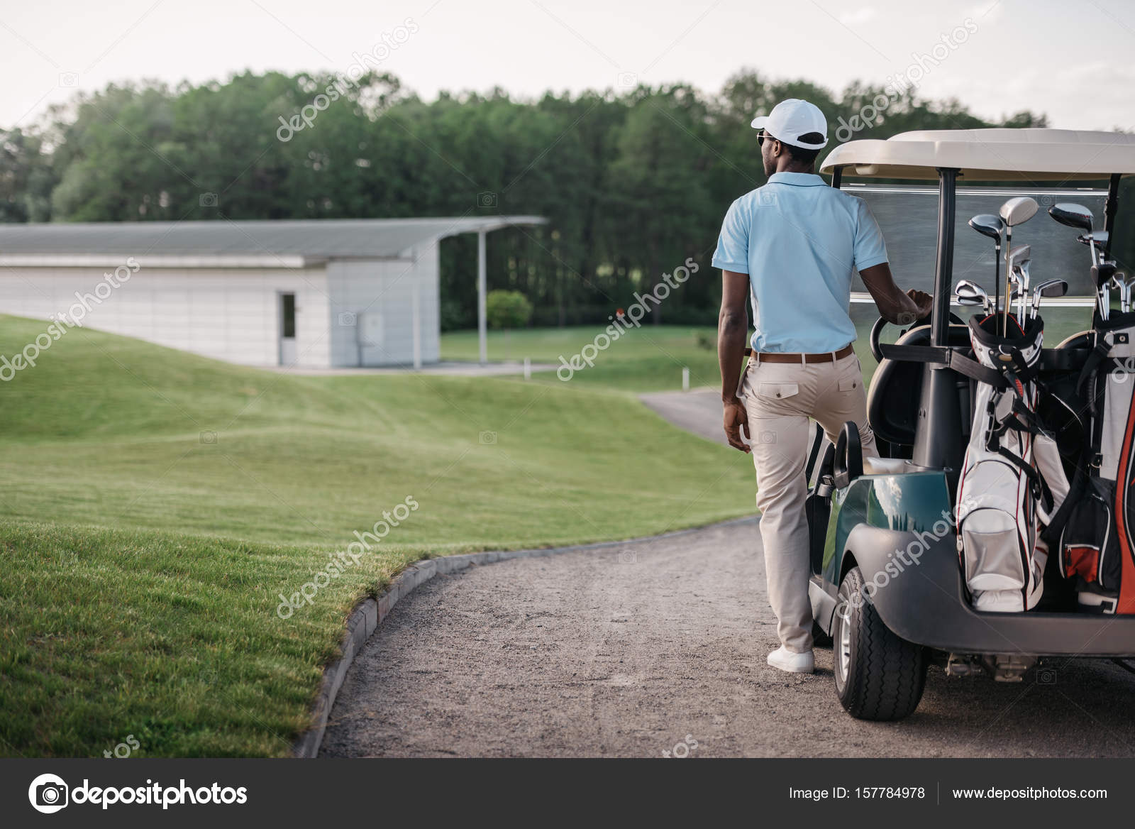 Golfer standing near golf cart Stock Photo by ©ArturVerkhovetskiy 157784978