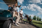 muži stojící poblíž golfový vozík