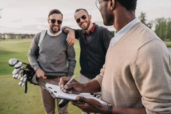 Man writing on paper in clipboard — Stock Photo, Image