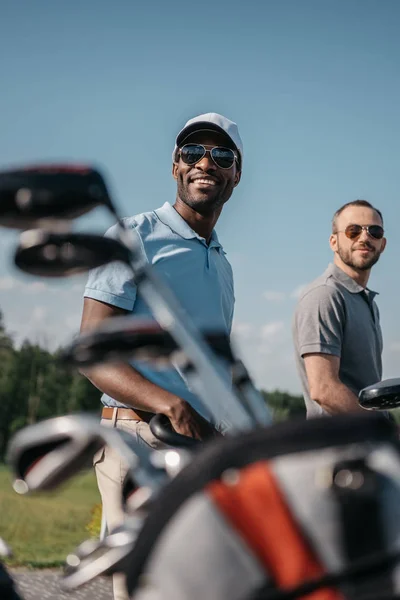 Des sportifs souriants se rendent sur un terrain de golf — Photo