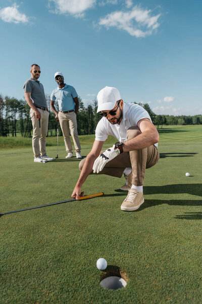 игрок в гольф смотрит на мяч возле лунки
