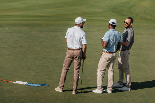 professional golfers talking on green pitch