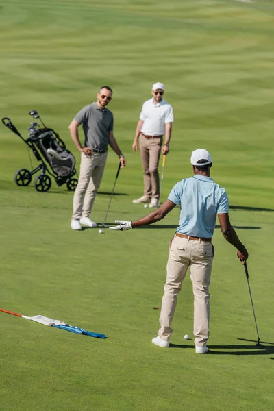 Golfistas multiétnicos hablando durante el juego — Foto de Stock