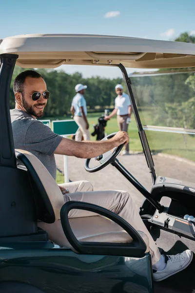 Young man sitting at golf cart — Stock Photo, Image