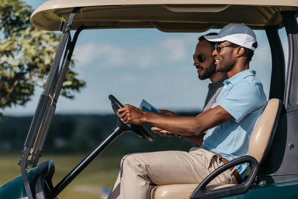 Friends talking while riding golf cart