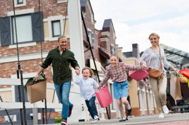 Family running with shopping bags on street clipart