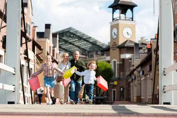 Famiglia in esecuzione con borse della spesa in strada — Foto Stock