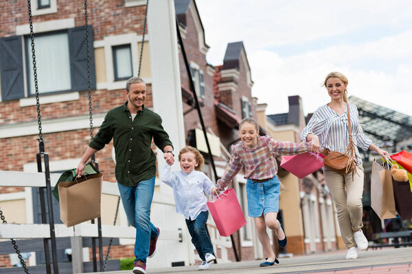 Family running with shopping bags on street