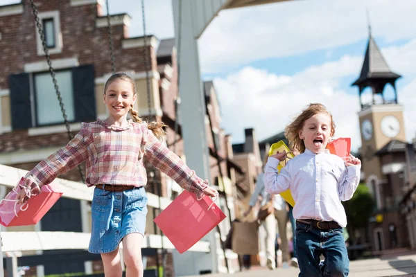 Children running with shopping bags — Stock Photo, Image