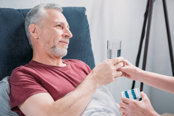 woman giving medicines to husband