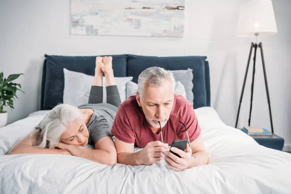 Coppia con smartphone a letto — Foto Stock