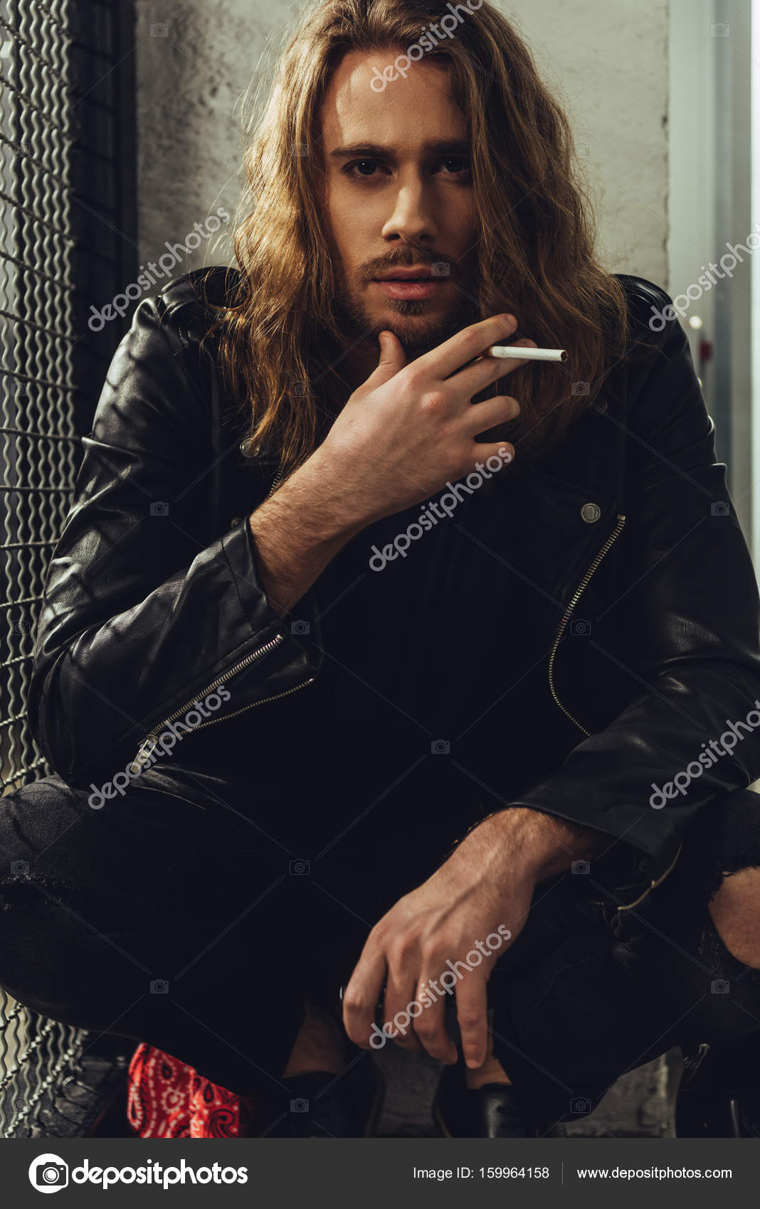 Stylish long haired man with cigarette Stock Photo by
