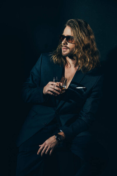 Человек в костюме пьет виски
