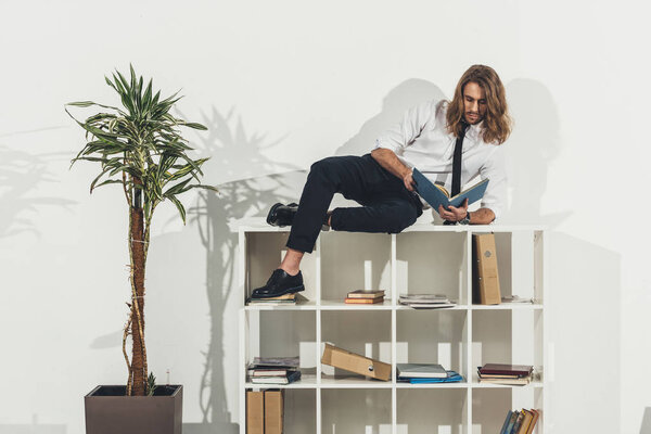 Businessman lying on bookshelf
