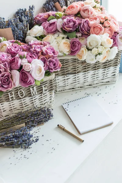 Flowers in wicker baskets and notebook — Stock Photo, Image