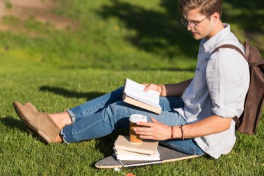 man reading book in park clipart