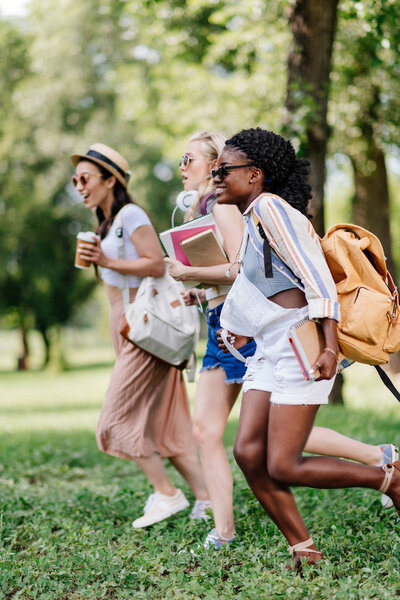 multiethnic girls with books running