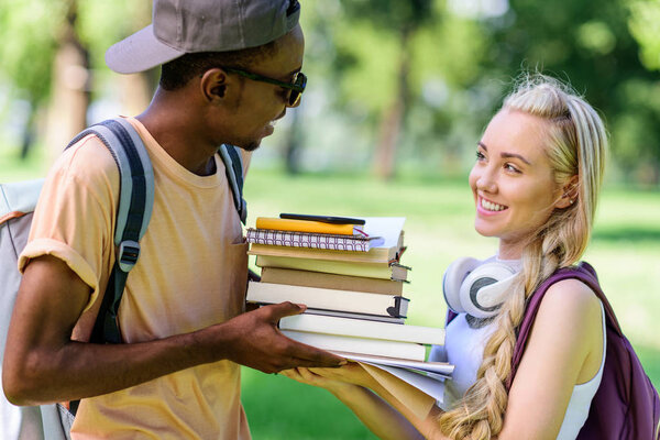 multiethnic couple with books in park