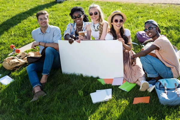 Multiethnic students holding banner — Stock Photo, Image