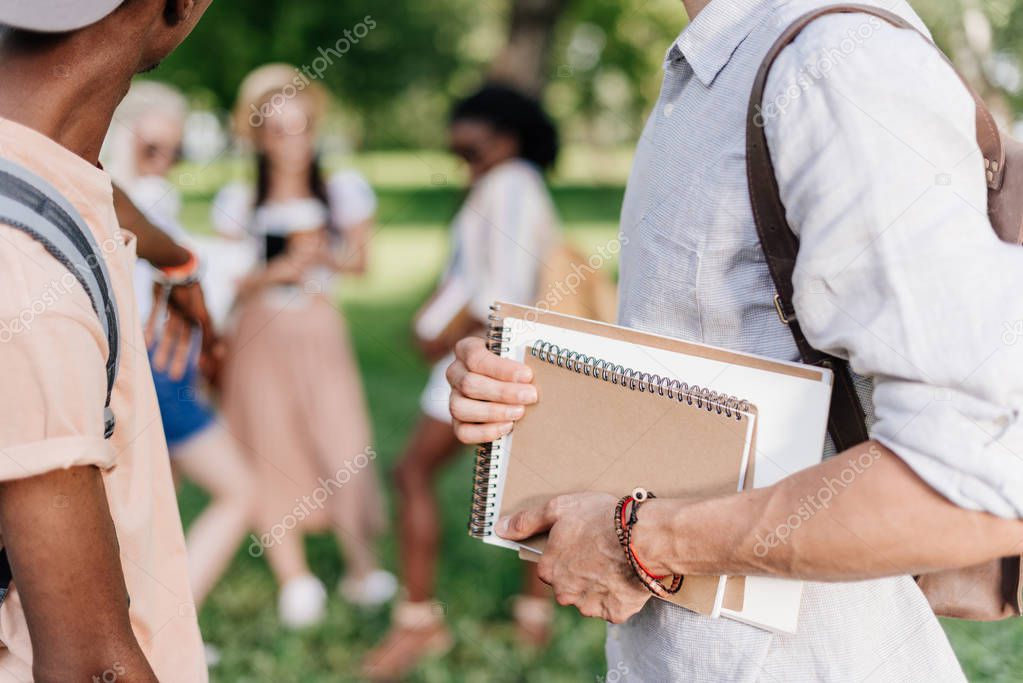 students with notebooks in park 