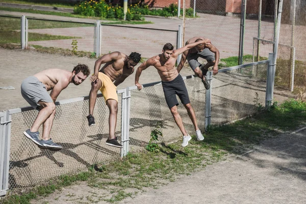 Handsome men jumping over fence — Stock Photo, Image