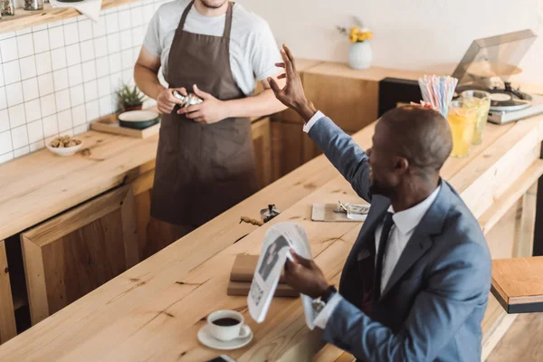 Empresario leyendo periódico en cafetería — Foto de Stock