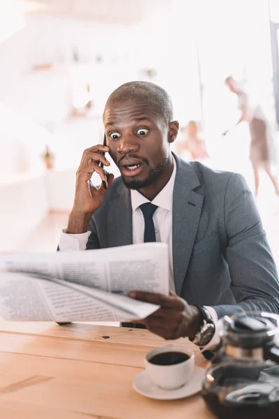 Geschäftsmann mit Smartphone liest Zeitung — Stockfoto