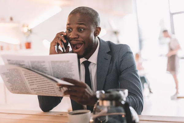 businessman with smartphone reading newspaper