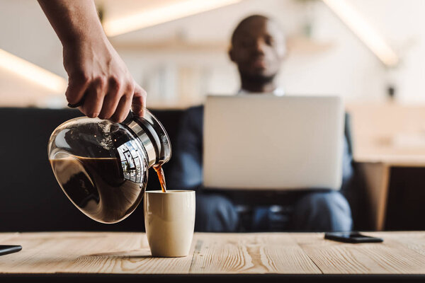 waiter pouring coffee into cup 