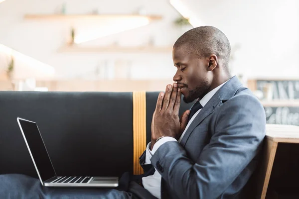 Businessman praying with laptop — Stock Photo, Image