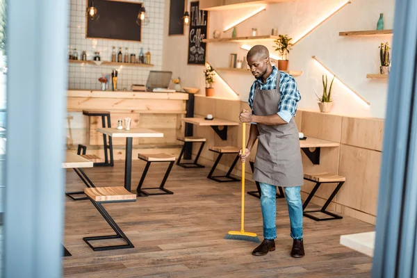 Man brooming in coffee shop — Stock Photo, Image