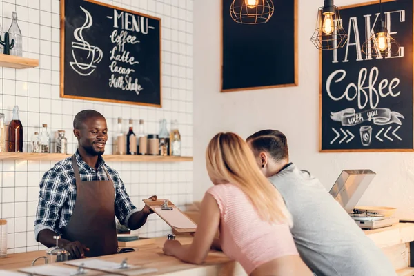 Barista δίνοντας μενού σε υπολογιστές-πελάτες — Φωτογραφία Αρχείου