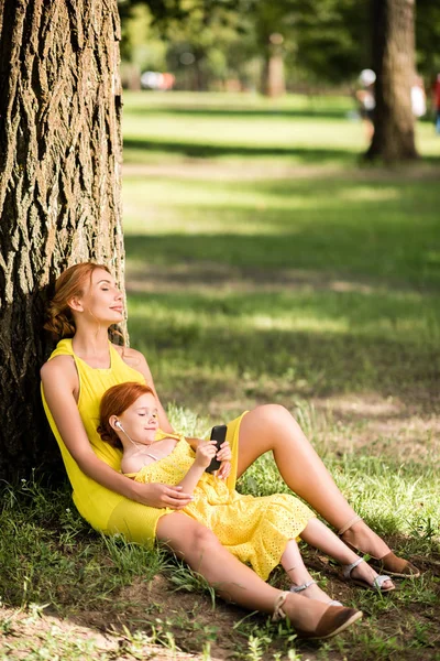 Mãe e filha com gadget no parque — Fotografia de Stock