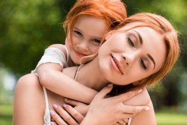 mother and daughter hugging at park clipart
