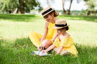 mother and daughter drawing in park clipart