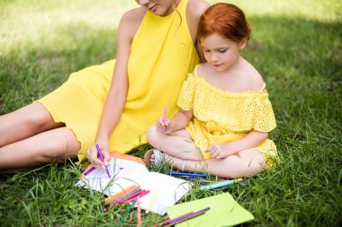 mother and daughter drawing in park clipart