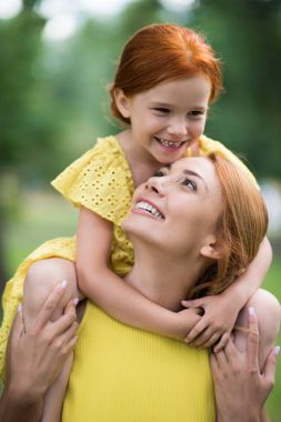 mother carrying daughter daughter on shoulders clipart