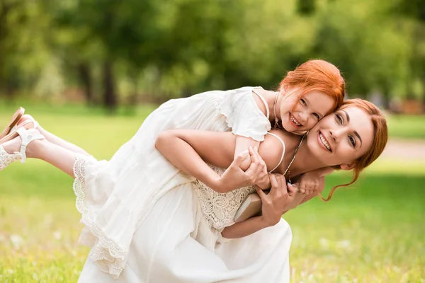 Mother piggybacking daughter in park — Stock Photo, Image