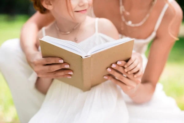 Mother and daughter with book at park — Stock Photo, Image