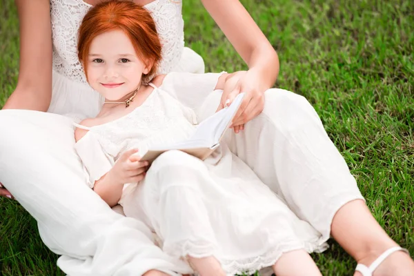 Moeder en dochter met boek bij park — Stockfoto