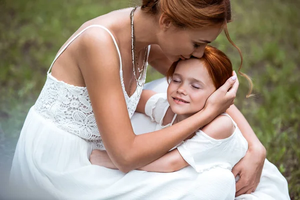 Mother kissing daughter at park — Stock Photo, Image