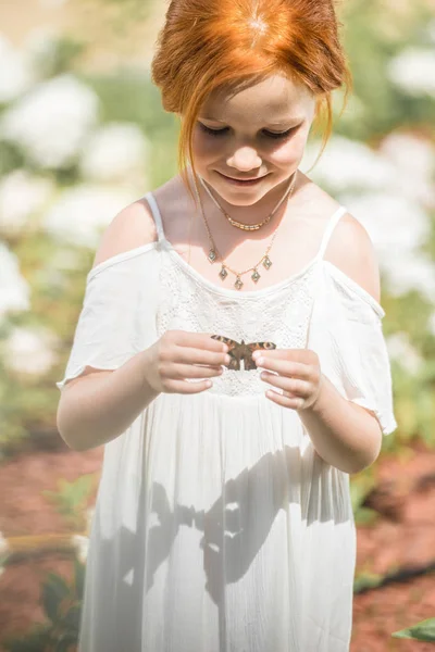 Little girl holding butterfly — Stock Photo, Image