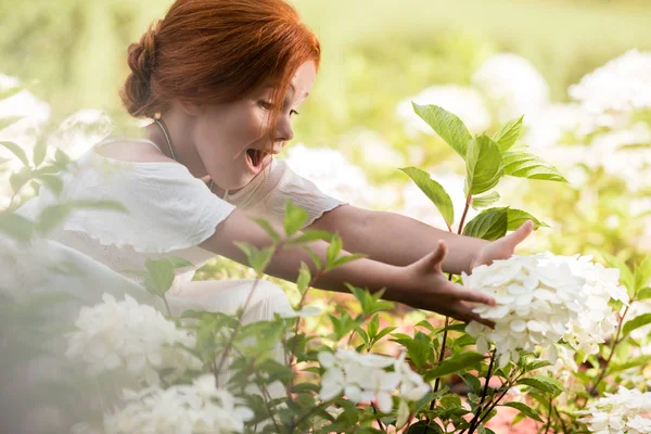 Redhead girl in flower bed — Stock Image Redhead girl in flower bed Stock Picture