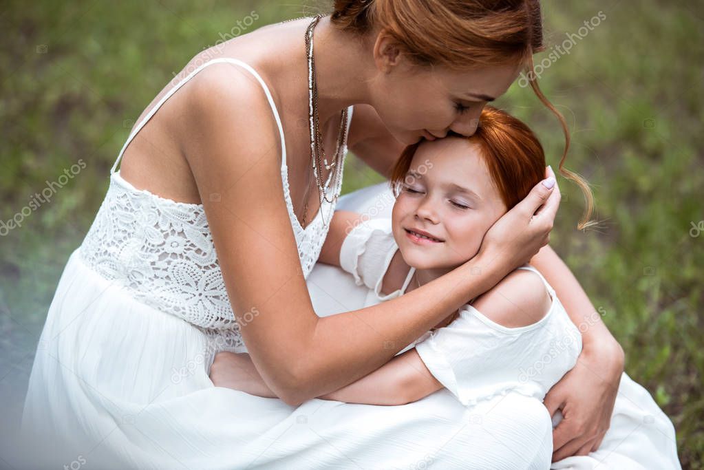 mother kissing daughter at park