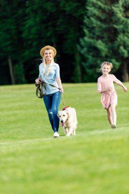 Parkta köpeği olan bir anne ve kız.