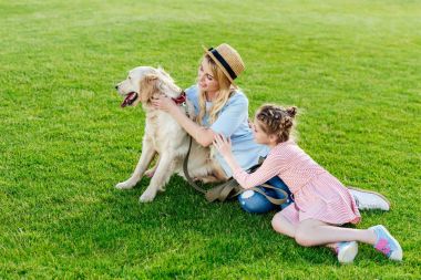 Parkta köpeği olan bir anne ve kız.